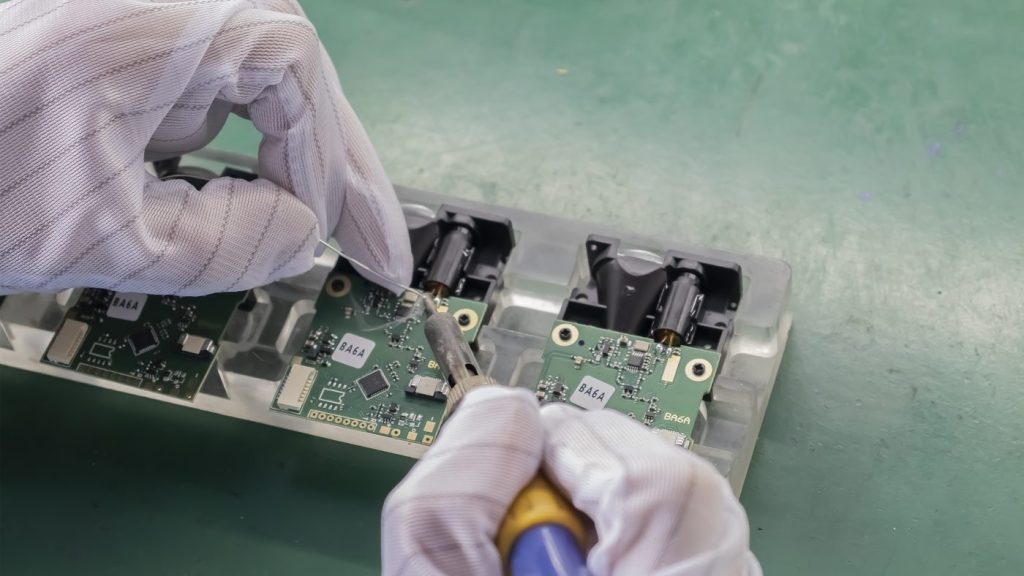 Technician assembling and reworking laser ranging sensor PCBs in the production workshop